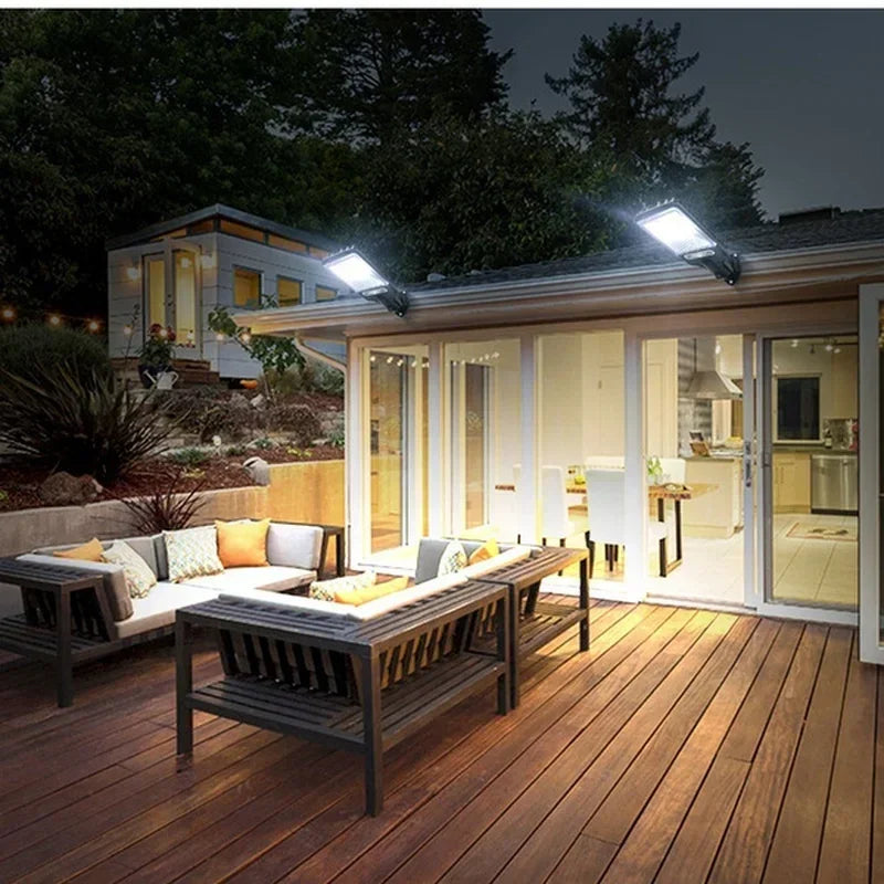Exterior view of a solar powered motion sensor security light illuminating a wooden deck and modern house.