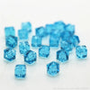 A pile of small, square cut blue glass crystal beads for jewelry making.