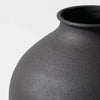 A close-up view of a large matte black decorative vase with a wide mouth and rounded body.