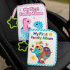 A pink and blue cloth baby photo album with a dinosaur and elephant design resting on a black seat.