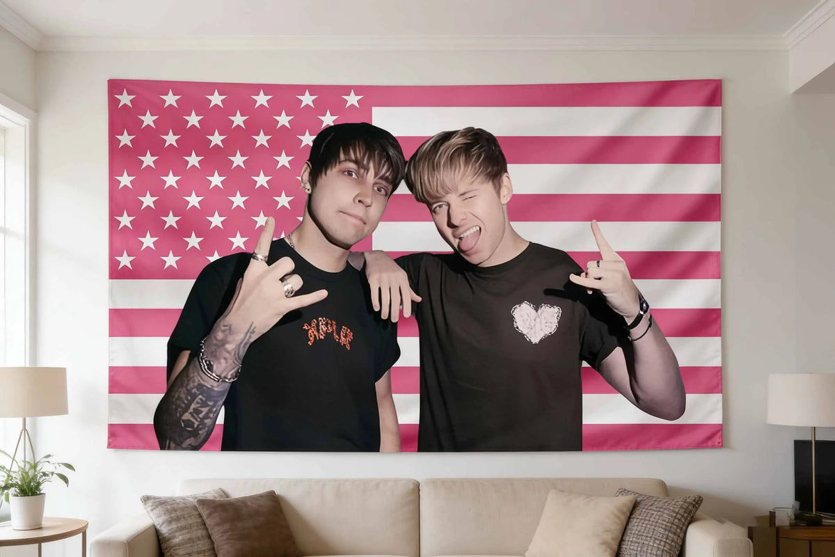 A man in a black shirt and a woman in a black shirt pose in front of an American flag tapestry wall art.