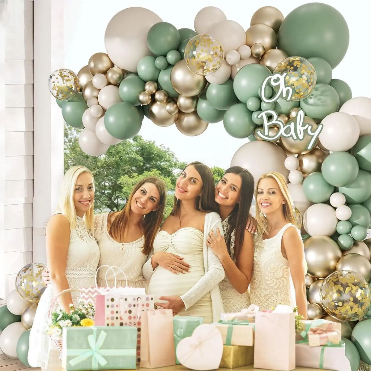 A balloon arch kit featuring sage green and gold balloons with white accents, surrounded by wrapped gifts.