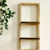 A light wood floating wall shelf with two tiers mounted on a white wall, decorated with green leaves and white roses.