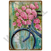 A vintage metal sign featuring a pink peony bouquet and a blue bicycle against a weathered teal background.