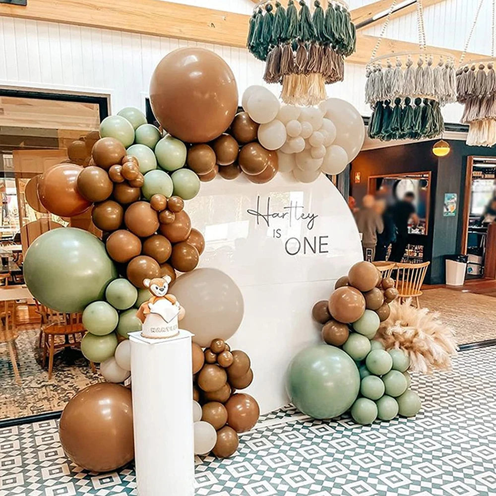 A large arrangement of sand and sage green latex balloons decorated for a celebration.