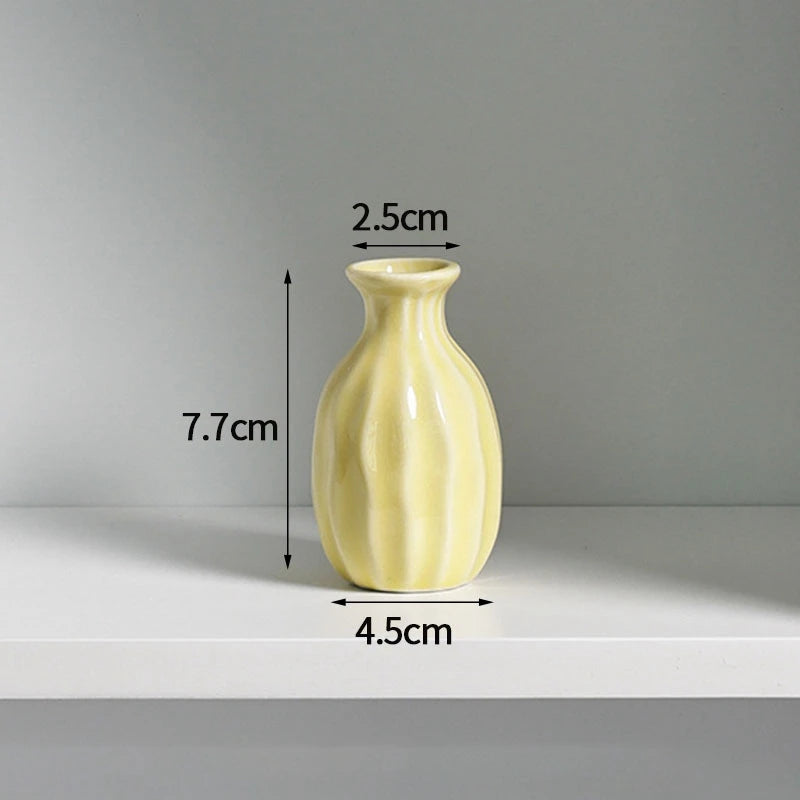 A light yellow ceramic mini vase with vertical ridges, shown against a gray background.