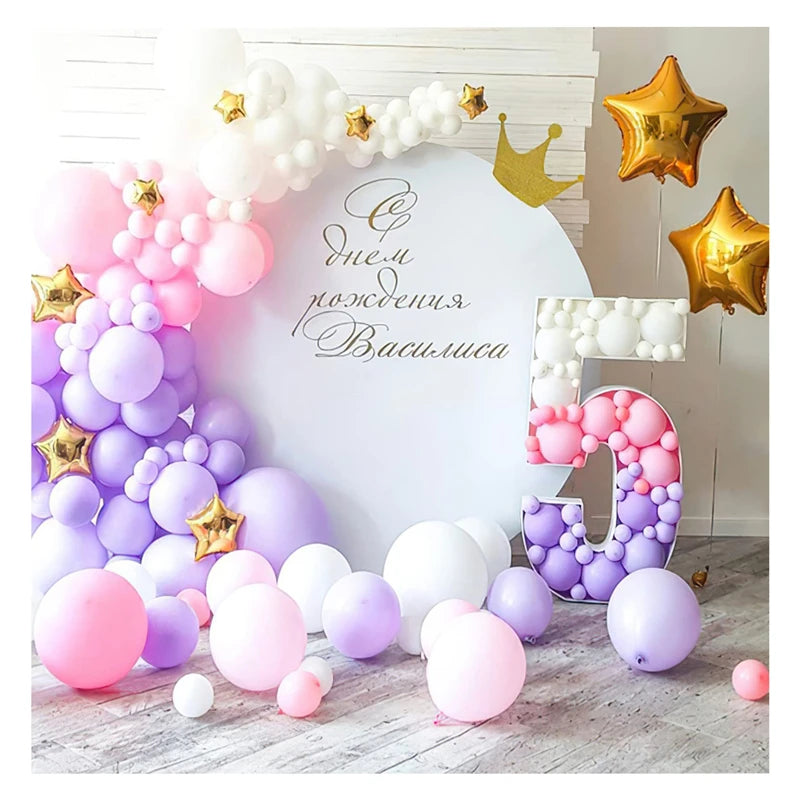 A white photo backdrop decorated with pink and purple balloons, gold stars, and large number balloons.