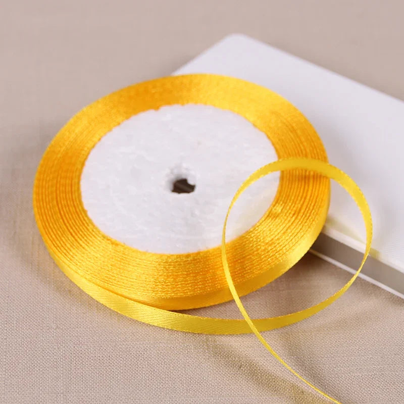 A spool of yellow satin ribbon with a white center core is shown on a light background.