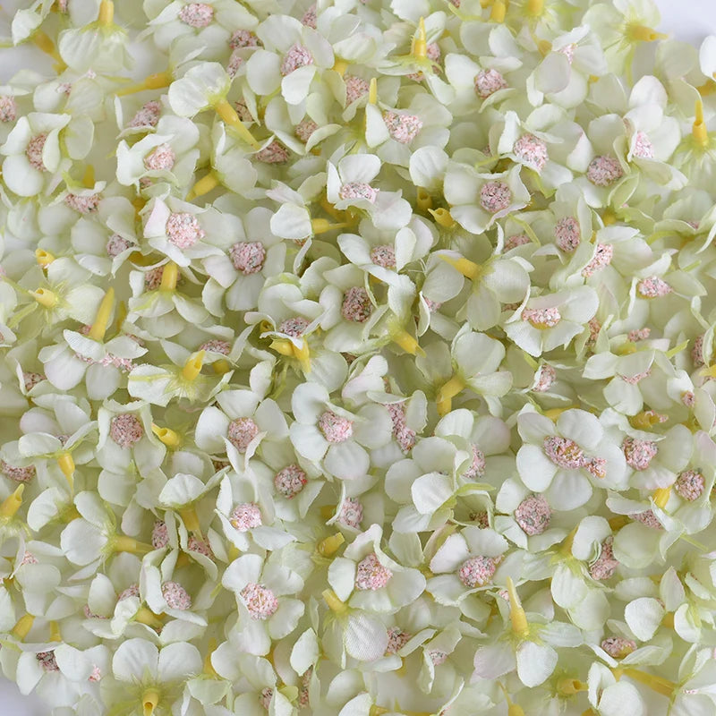A close-up view of silk artificial flower heads in pale green and white with pink accents.