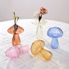 Collection de vases en forme de champignons en verre de couleurs rose, blanc et bleu, exposés sur une nappe en dentelle blanc
