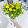 A hand holds a bouquet of bright yellow artificial lemon branch stems for decoration.