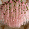 A lush pink silk wisteria hanging vine garland suspended from a ceiling.