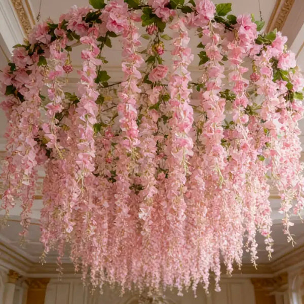 A lush pink silk wisteria hanging vine garland suspended from a ceiling.