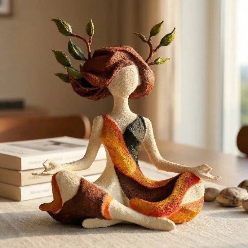 A resin sculpture of a yoga girl with reddish-brown hair and leafy antlers sitting on a light surface.
