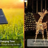 Solar-powered outdoor string lights illuminating a deer statue at night