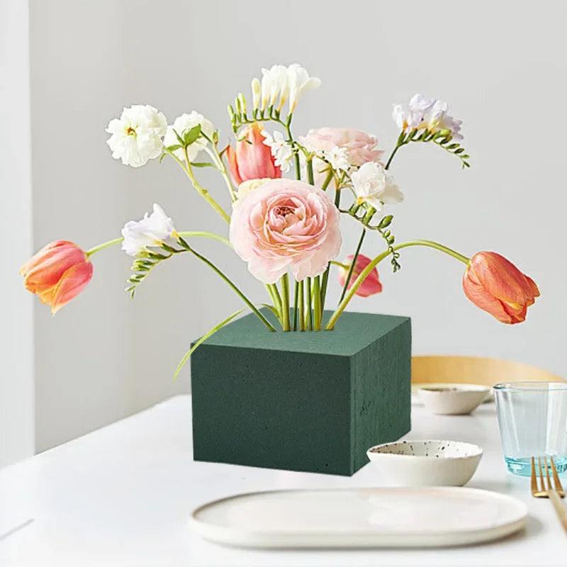 A bouquet of pink and white flowers arranged in a dark green block for party decor.
