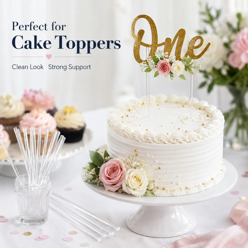 A white tiered cake decorated with floral accents and gold topper sticks on a white platter.