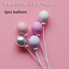 Five pastel balloons, including pink, purple, and silver, are displayed against a pink background.