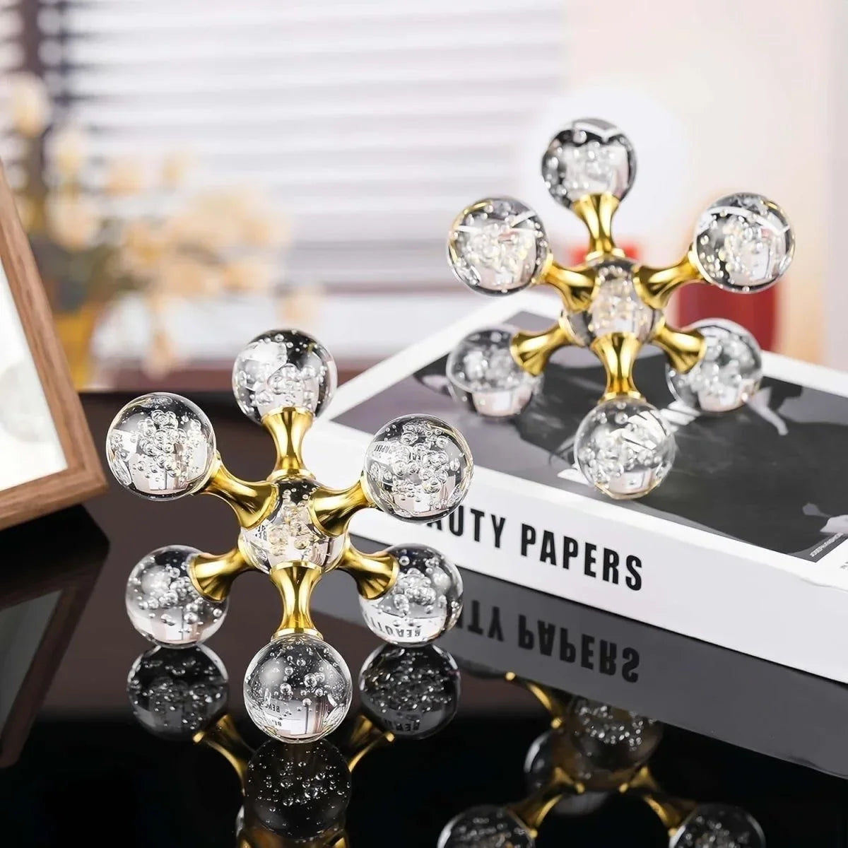 Gold molecular sculpture desk decor featuring clear glass spheres on a white box.