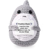 A gray crochet donkey figurine with a white inspirational card inside.