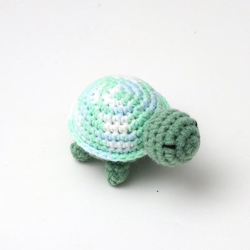 Handmade crocheted turtle plush toy in light green and pale blue colors.