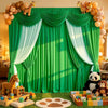 A green fabric backdrop with white draping and animal figures, set up for an event or photo shoot.