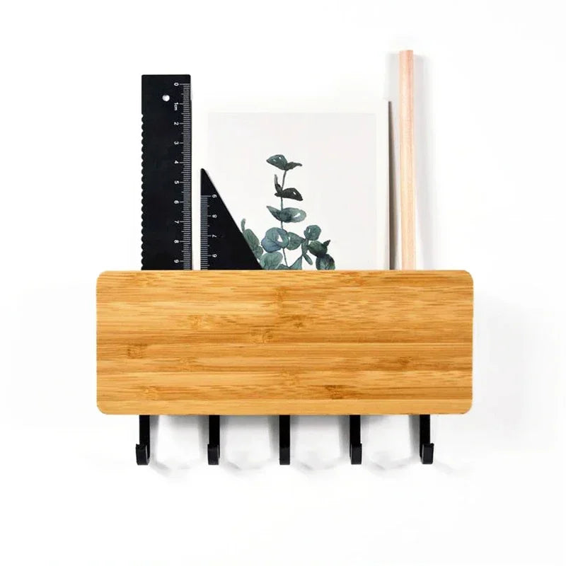 A wooden bamboo wall-mounted key rack with six hooks and a ruler displayed against a white background.