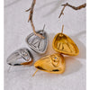 Three geometric stud earrings in silver and gold tones resting on a white surface.