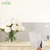 A bouquet of white roses displayed in a glass vase next to a display of self-adhesive heat resistant wall tiles.
