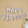 Silver foil letter balloons spelling out Happy Birthday strung across a beige wall for party decoration