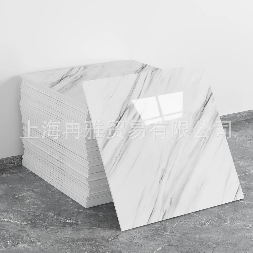 A stack of rectangular faux marble 3D self-adhesive wall tiles with white veining displayed on a gray floor.