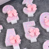 Pink glitter number cake candles shaped like a number with a bow on a gray background