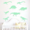 Wall decals of various green dinosaurs decorating a white crib