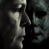 A dark, dramatic movie poster featuring two faces, one modern and one menacing, with the title Halloween.