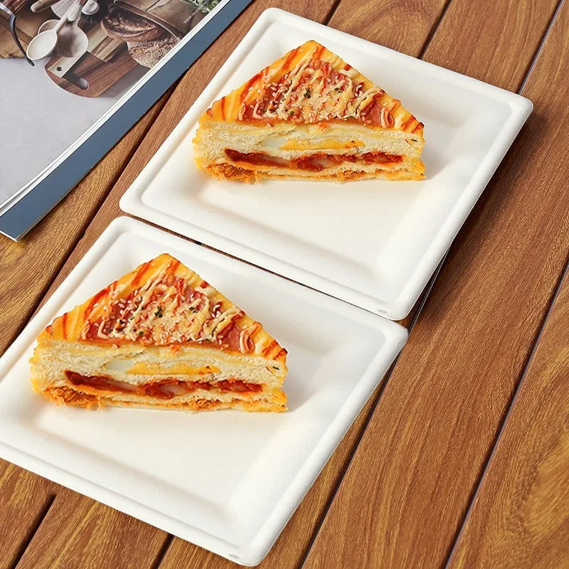 A slice of layered sandwich or cake served on a white square paper plate.