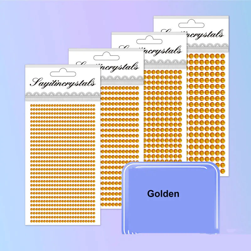 A collection of gold and silver rhinestone embellishment packs are displayed, with a single golden pack in the foreground.