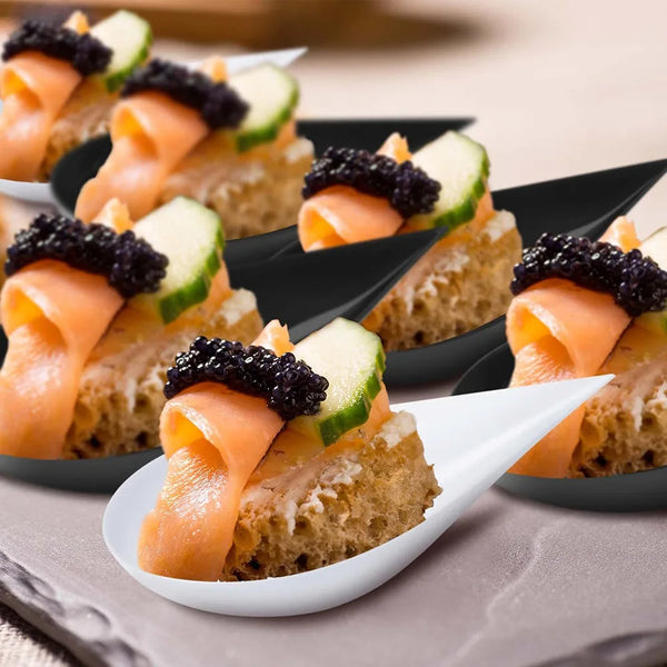 Mini appetizer plates filled with smoked salmon, cucumber slices, and black caviar served in tasting cups.