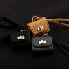 A set of mini leather openable bags in black and tan with gold hardware displayed on a dark surface.