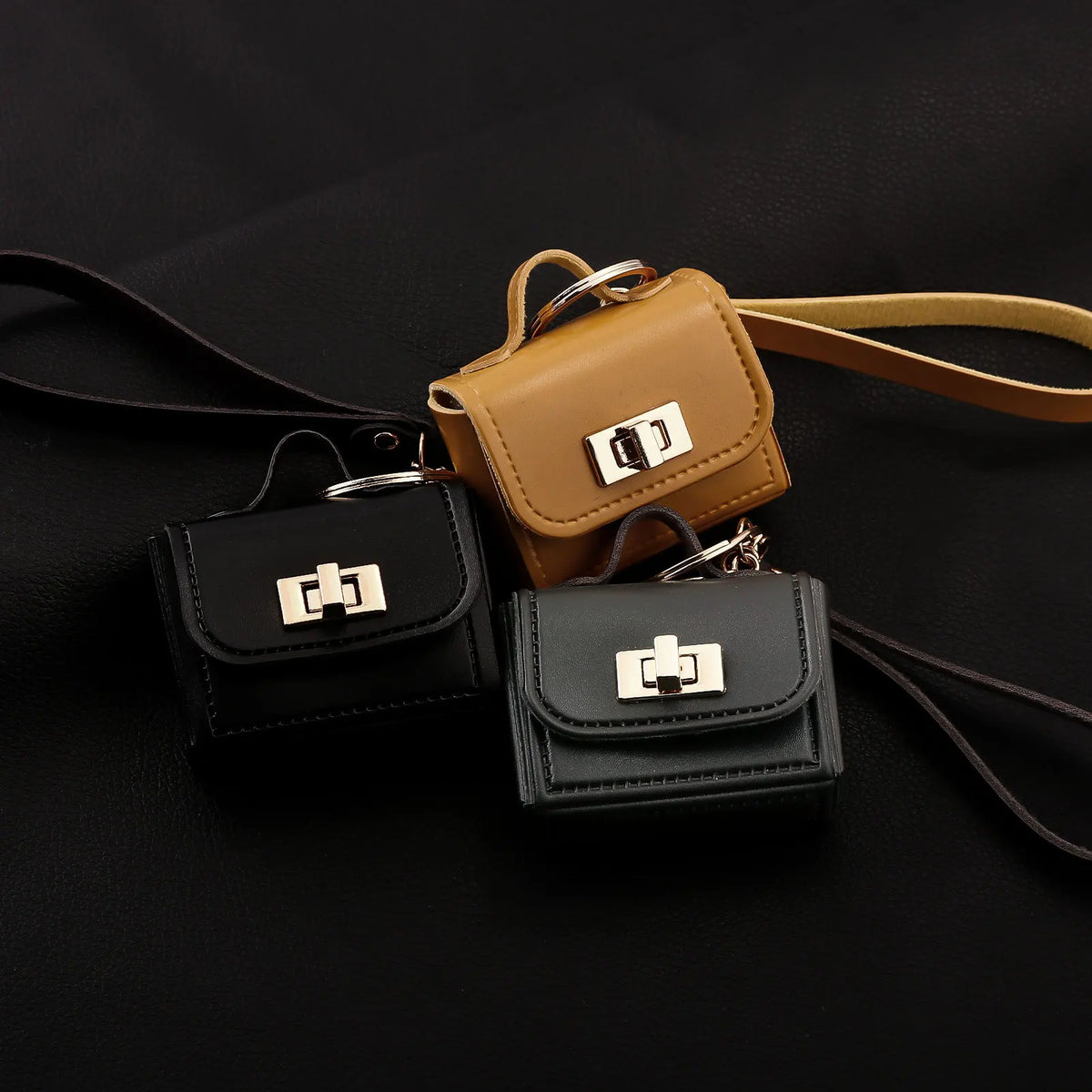 A set of mini leather openable bags in black and tan with gold hardware displayed on a dark surface.