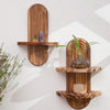 Two wooden wall shelves with natural grain displaying small decorative items and a potted plant.