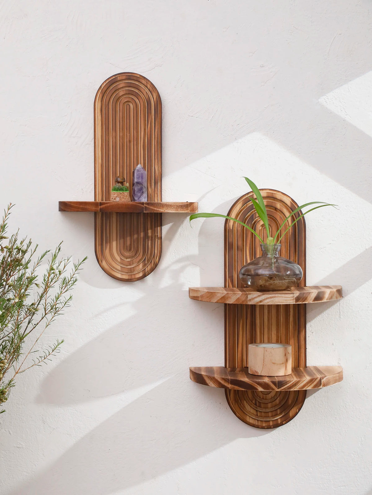 Two wooden wall shelves with natural grain displaying small decorative items and a potted plant.