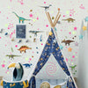 A teepee decorated with glow-in-the-dark dinosaur wall stickers and stuffed animals for a child's room