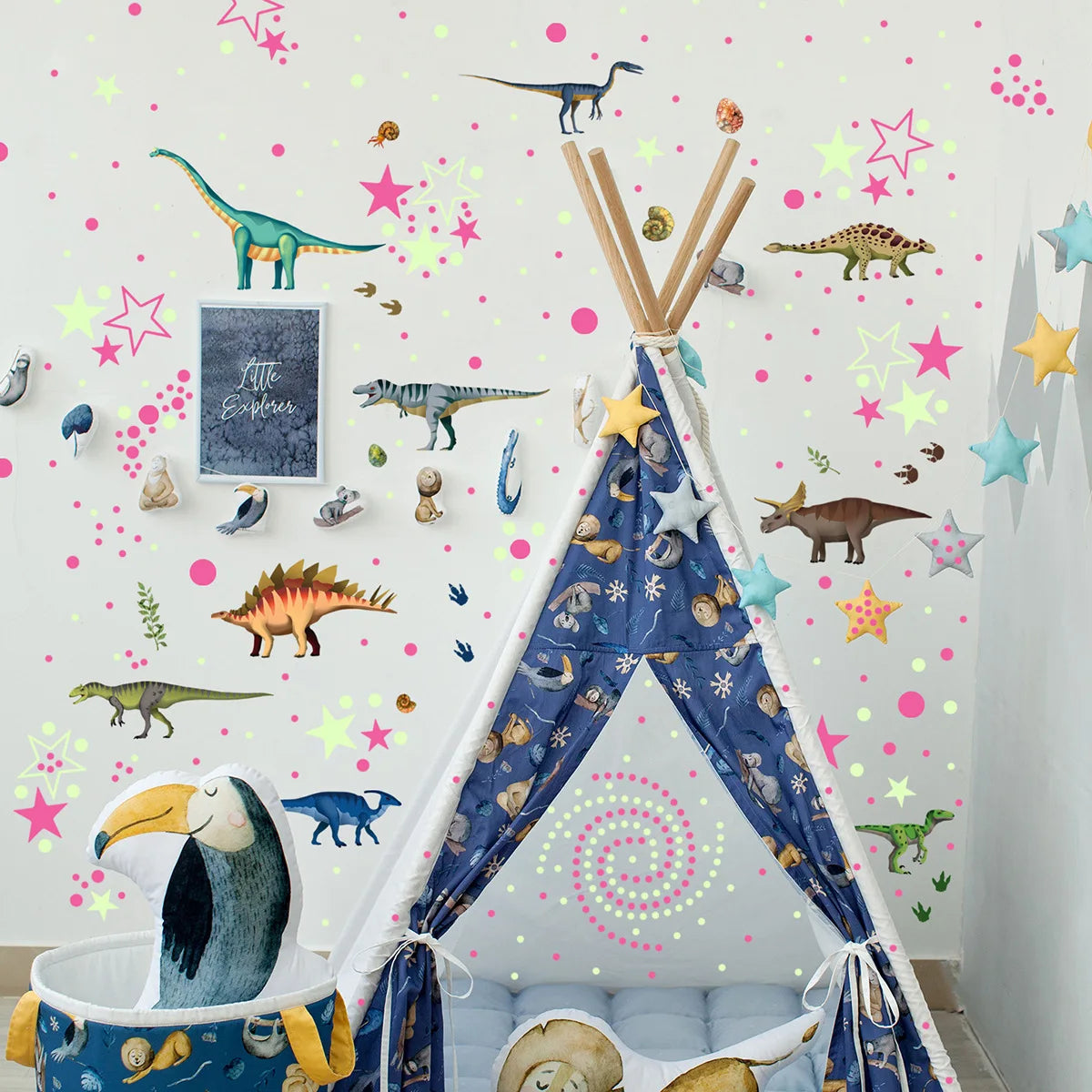 A teepee decorated with glow-in-the-dark dinosaur wall stickers and stuffed animals for a child's room