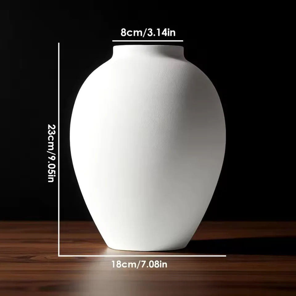 A white ceramic vase with a smooth, rounded shape is shown on a wooden surface.