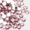 A close-up view of pink and clear round flatback resin rhinestones scattered on a white background.