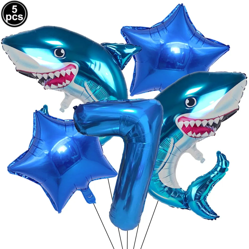 A set of blue shark foil balloons and a number seven balloon for an ocean-themed party decoration