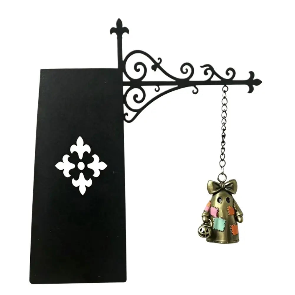 Black metal scrollwork lamp holder with a small brass figurine.
