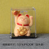 A small, light orange solar-powered figurine of a smiling cat with red accents displayed in a clear box.