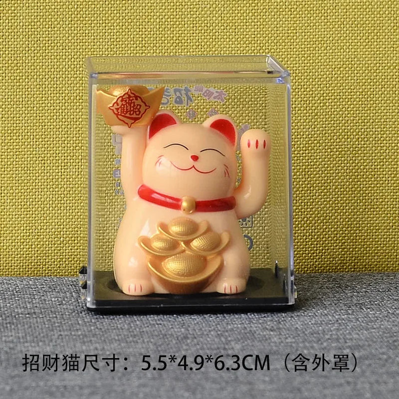 A small, light orange solar-powered figurine of a smiling cat with red accents displayed in a clear box.