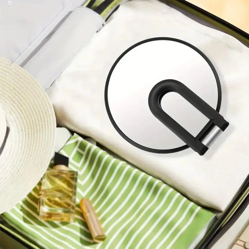 A precision dual-magnification handheld mirror is shown inside a green striped pouch with a white cloth lining.